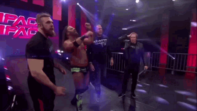 a group of wrestlers are walking down a ramp in a wrestling ring .