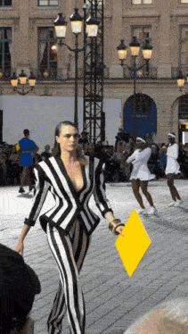 a woman in a black and white striped suit is walking down a street