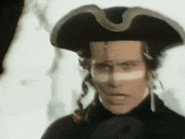 a man with white paint on his face wears a pirate hat