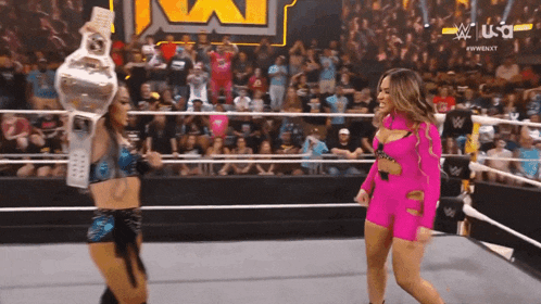 two women are wrestling in a ring and one is holding a trophy .