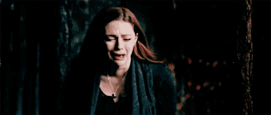 a woman is crying in a dark room with her eyes closed and her mouth open .