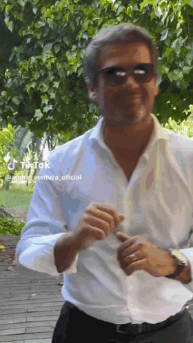 a man wearing sunglasses and a white shirt is dancing .