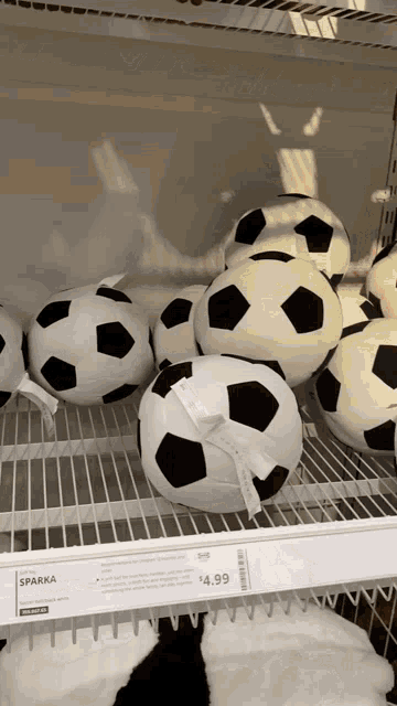 a bunch of stuffed soccer balls on a shelf with a price tag of $ 4.99