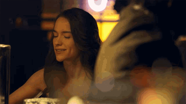 a woman sits at a table with her eyes closed and smiles