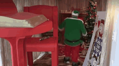 santa claus is standing in front of a christmas tree in a room