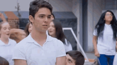 a boy in a white shirt stands in front of a group of students