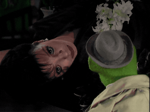a woman is laying down with a green muppet and the words mm buh-bye are visible