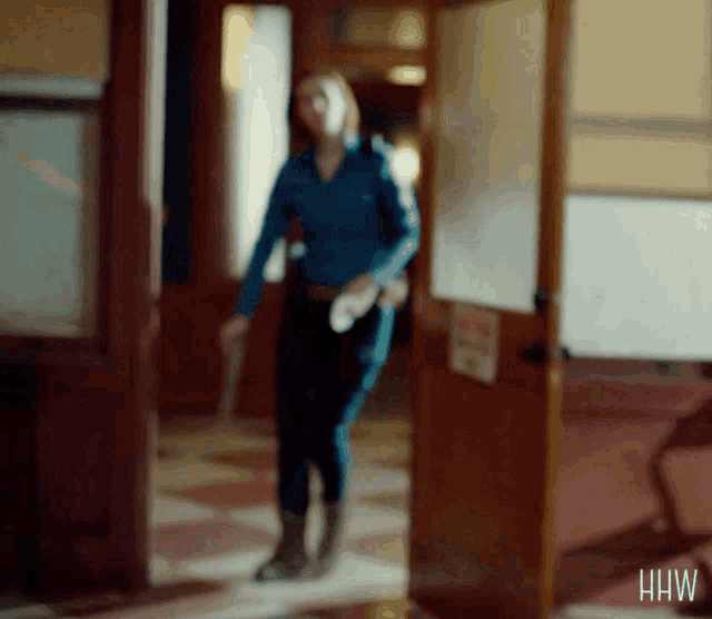 a blurry picture of a woman walking in a hallway with the letters hhw on the bottom right