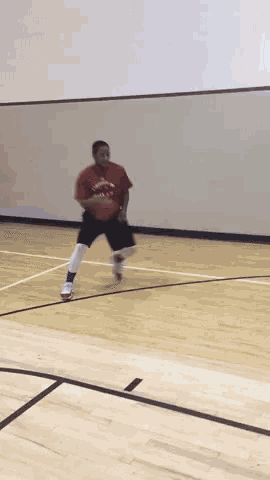 a man in a red shirt is dribbling a basketball on a court