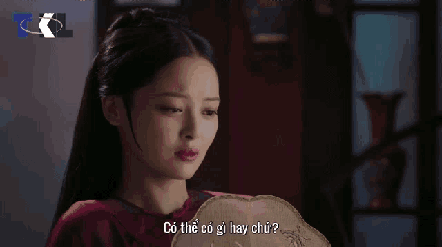 a woman holding a fan with the words có thể có gì hay chứ written on the bottom