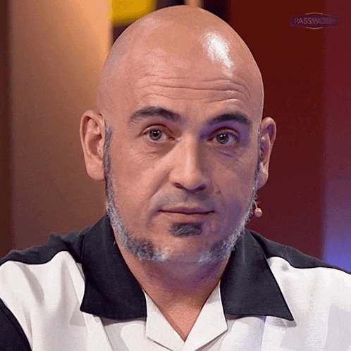 a bald man with a beard and mustache looks at the camera with a microphone in front of him that says passmaster