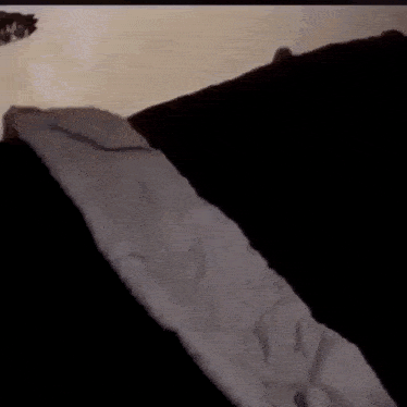 a white blanket is laying on a black couch