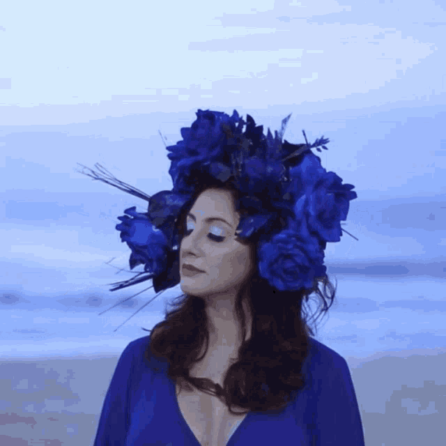 a woman wearing a crown of blue flowers on the beach