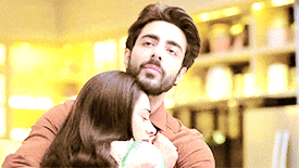 a man with a beard is hugging a woman with long brown hair .