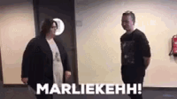 a man and a woman are standing next to each other in a hallway and the woman is talking to the man .