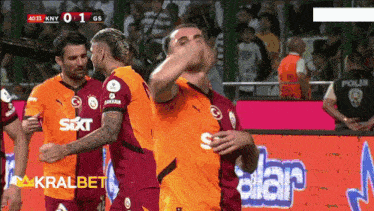 a group of soccer players are celebrating a goal in front of a sign that says kralbet