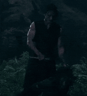 a man in a black shirt is holding another man 's head in the dark
