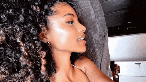 a close up of a woman 's face with curly hair and earrings .