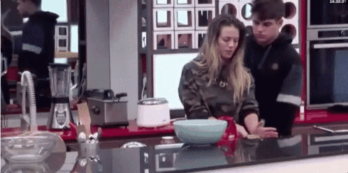 a man and a woman are standing at a kitchen counter .