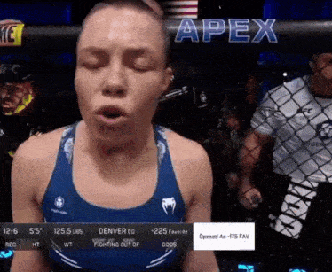a woman in a blue tank top is standing in front of a cage with the word apex on it