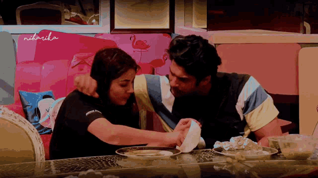 a man and a woman are sitting at a table with niharika written on the corner