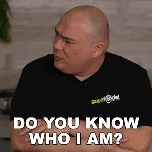 a bald man wearing a black shirt that says " do you know who i am " on it