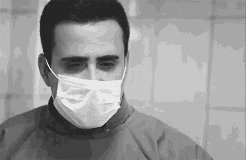 a man wearing a surgical mask looks sad