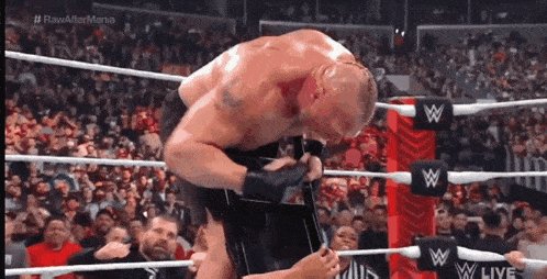 a wrestler is kneeling down in a wrestling ring while a crowd watches .