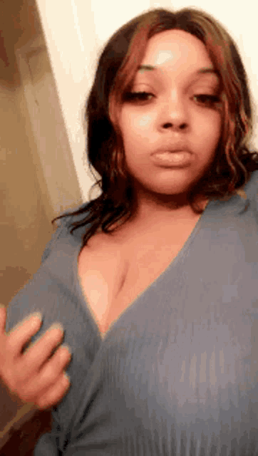 a woman with very large breasts is taking a selfie with her hands on her chest .