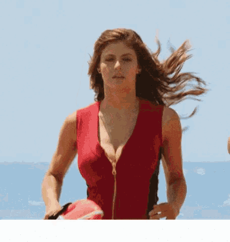 a woman in a red swimsuit is holding a life preserver on the beach .