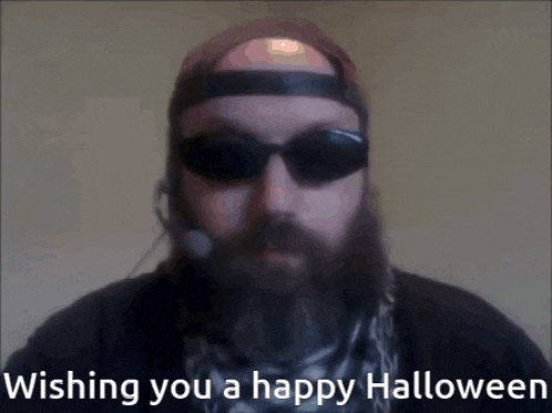a man with a beard wearing sunglasses and a headset says " wishing you a happy halloween "