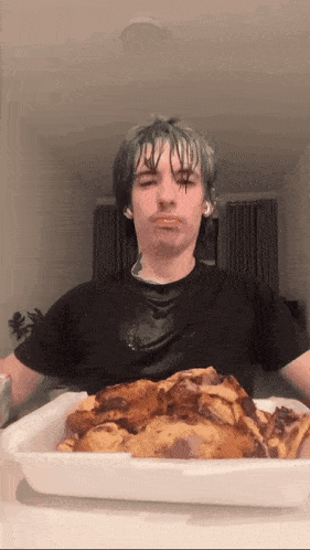 a man is eating a tray of food with his mouth covered in food