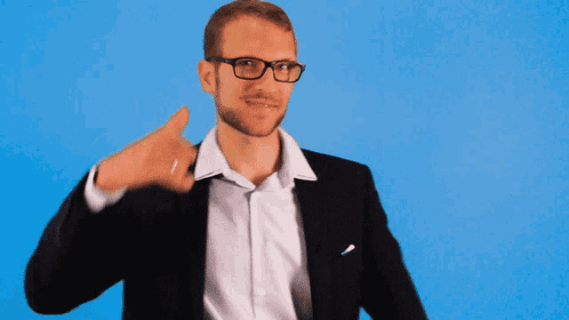 a man wearing glasses and a suit making a call me sign