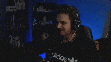 a man wearing headphones and an adidas shirt is sitting in front of a computer .