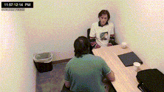 a man is sitting at a table with another man and the time is 11:57