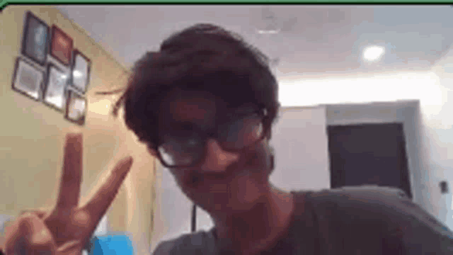 a man wearing glasses is giving a peace sign