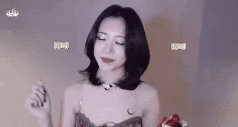a woman is standing in front of a wall with her eyes closed and a necklace around her neck .