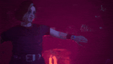 a woman is dancing in a dark room with red lights