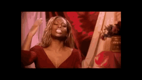 a woman in a red dress is blowing a bubble with her mouth open .