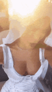 a woman in a white dress is taking a selfie with her breasts out .