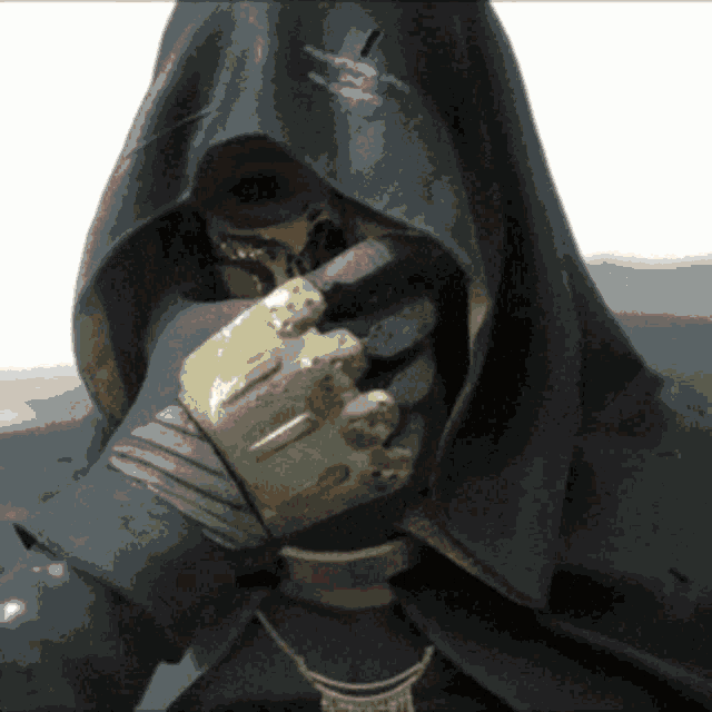 a person with a hood on covering their face with a hand