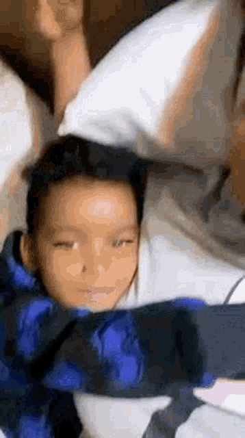 a little boy is laying on a bed with a blue and black blanket .