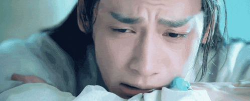 a close up of a man laying on a bed with his head on a blanket .