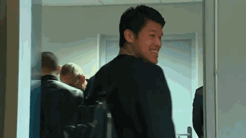 a man in a black shirt is smiling in a doorway