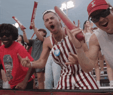 a man wearing a red hat that says trojans holds a red cone