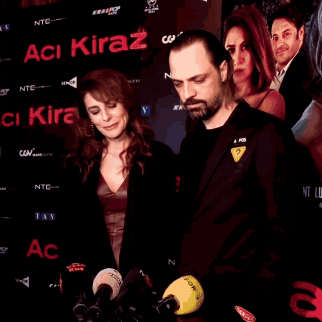 a man and a woman are standing in front of a wall that says " aci kiraz "