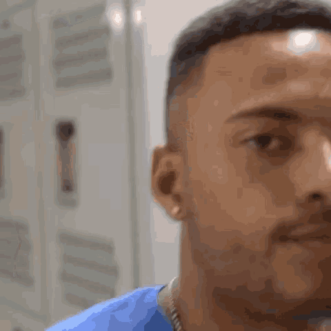 a close up of a man 's face in a locker room with a blurred background .
