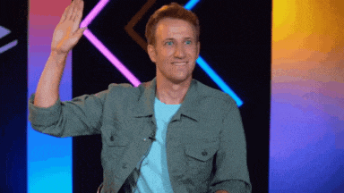 a man in a green jacket waving his hand