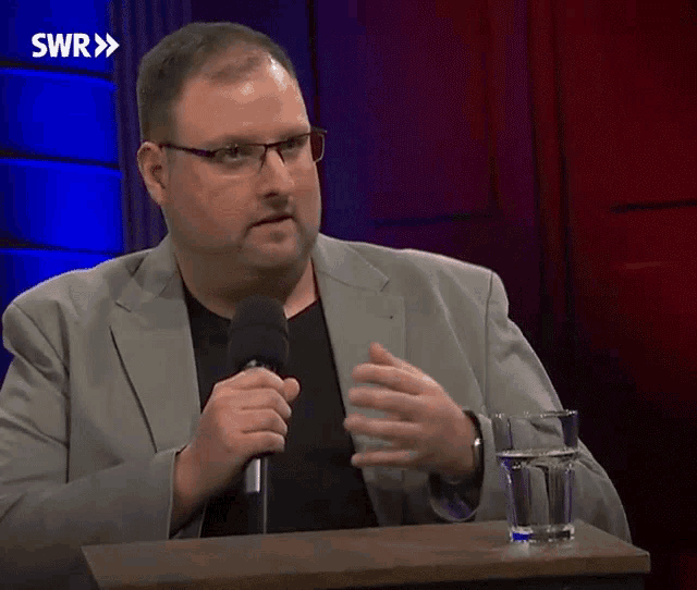 a man speaking into a microphone in front of a swr logo