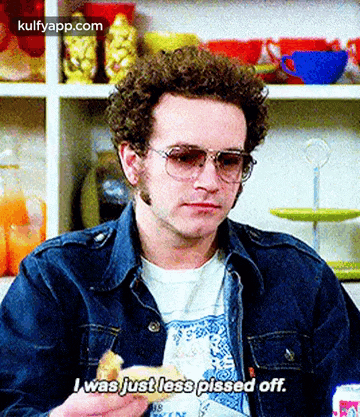a man wearing sunglasses and a denim jacket is holding a sandwich and saying i was just less pissed off .